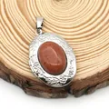 Macro detail of oval locket with sparkling goldstone and floral relief on wood background - Oval Goldstone