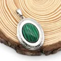 Macro shot of oval locket pendant with malachite stone on natural wood background - Oval Malachite