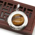 Close-up of vintage silver locket with tiger eye stone and floral relief on a wooden box - Round Tiger Eye