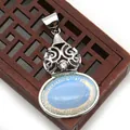 Macro shot of silver filigree peacock pendant featuring an oval light blue stone - Opal