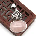 Macro shot of oval pink quartz pendant with intricate silver metal floral filigree detail - Rose Quartz