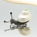 Detalle macro de broche de caracol de concha natural con cuerpo de metal plateado y cristales - 26x54mm / Estilo Turbo Plateado (B250606055)