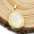 Detail van ovale gouden medaillon met parelmoer inleg op natuurlijke houten ondergrond - 19x28mm / Wit (Parelmoer)