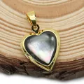 Dettaglio di un medaglione a cuore in oro con madreperla su una superficie in legno - 17x21mm / Madreperla nera