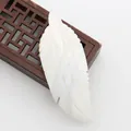 Macro detail of hand-carved white mother of pearl shell pendant in realistic feather shape - White Shell Feather Shape