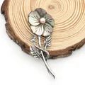 Detail of flower brooch with dark shell petals and a pink pearl on a wooden texture - Dark Grey Iridescent Style (Blue Turquoise)