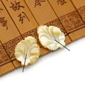 Vue macro de perles de nacre sculptées en forme de feuille avec reflets irisés naturels - Nacre Jaune Forme Feuille (14x19mm)