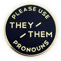 Broche redondo de esmalte con borde dorado y texto "PLEASE USE THEY / THEM PRONOUNS" en negro - elle