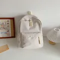 Minimalist cream nylon backpack for students featuring a woven rope zipper detail - White