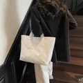 White Tyvek tote bag with embossed letters worn by a model in a fashion street setting - Large / White