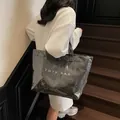 Minimalist black tote bag with transparent outer layer and white text held by model - Large / Black