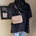 Bolso bandolera cuadrado minimalista en cuero rosa nude llevado al hombro con traje - Rosa