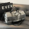 Borsa sportiva cilindrica grigia con cinghie nere su un divano di pelle - Grigio