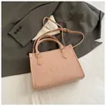 Pink woven tote bag with Paris embroidery and crossbody strap on a grey suit jacket - Small Pink