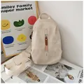Detail of a beige canvas crossbody bag with contrast zipper pull against a stylish wall - With Charm / Off White
