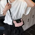 Pink and black bow shoulder bag with heart pendant and adjustable strap worn by model - Pink