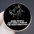 Round cartoon pin with funny stick figure pushing another off a cliff and witty quote - Stickman Pushing Style (Some People Just Need A Push In The Right Direction)