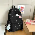 Black quilted backpack with bow embroidery and star patches on a wooden table - With Star Charms / Black