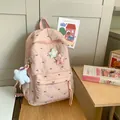 Pink quilted backpack with bow embroidery and star badges in a cozy desk setting - With Star Charms / Pink