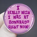 Pink enamel Bonnaroo music festival lapel pin with purple text slogan held in hand - Pink Purple