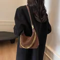 Braune Retro Wildleder-Umhängetasche mit goldener Kette auf schwarzem Wollmantel - Kaffeebraun