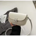 Detail of minimalist cream saddle bag featuring woven fabric and silver S buckle - Off White