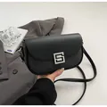 Detail showing the square silver buckle and textured black fabric on the saddle bag - Black