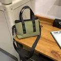 Olive green nylon tote bag with black strap handles and adjustable shoulder strap - Olive Green