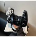 Detail der glänzenden schwarzen Tasche mit Perlenbogen und Spitzenbesatz-Zubehör - Perlen Schleife Spitze Dekoration Stil / Schwarz
