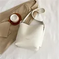 Bolso saco minimalista en cuero blanco crema con acabado texturizado y letras doradas - Blanco Roto