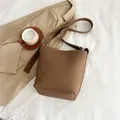 Bolso cubo de cuero marrón con grano de lichi y correa ancha sobre tela - Marrón