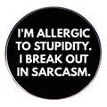 Runde schwarze Emaille-Brosche mit sarkastischem weißem Text I'm allergic to stupidity - Allergisch Gegen Dummheit
