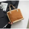 Detail shot of brown suede tote bag featuring plush white lamb wool trim and leather handles - Brown