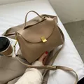 Schicke khakifarbene Kunstledertasche mit Goldverschluss auf strukturiertem Blazer-Hintergrund - Khaki