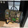 Detail of army green travel bag featuring vintage embroidery patches and leather trim - Green