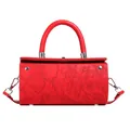 Close-up of bright red cylindrical bag with embossed floral pattern and metal studs - Red