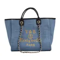 Dettaglio della borsa tote in denim blu con ricami gialli, manici in pelle nera e catena - Azzurro