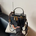 Elegante bolso caja de cuero negro con herrajes dorados y detalle de colgante tejido - Negro