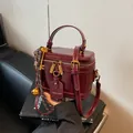 Bolso caja de cuero burdeos profundo con doble cremallera, asa y colgantes metálicos - Burdeos