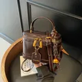 Elegante bolso de mano vintage marrón oscuro con herrajes dorados y etiqueta de marca - Marrón