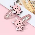Détail de jolies barrettes lapin rose avec pompons doux et bordures pailletées chic - Rose