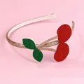Detalle de diadema de cereza roja con hojas de purpurina dorada en fondo rosado - Cherry Headband