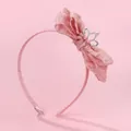 Détail d'un serre-tête rose avec nœud en dentelle et couronne ornée de perles fines - Rose