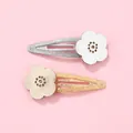 Détail de barrettes à fleurs pailletées avec motifs découpés au laser sur fond rose - Barrettes à Cheveux Fleurs Or Et Argent