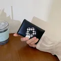 Schwarzes Leder-Kartenetui mit schwarz-weißem Blumenverschluss in der Hand - Schwarz