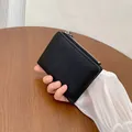 Piccolo portafoglio nero in pelle martellata con cerniera argento tenuto in mano - Nero
