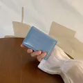 Portafoglio azzurro con trama a coccodrillo tenuto davanti a un tavolo in legno - Blu