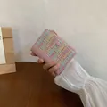 Portafoglio piccolo in pelle PU intrecciata rosa con motivi colorati tenuto in mano - Rosa