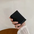 Mini minimalist black tri-fold wallet for women featuring a 3D floral accent in matte finish - Black