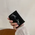 Black leather wallet featuring white bow prints and central pearl decorations - Black
